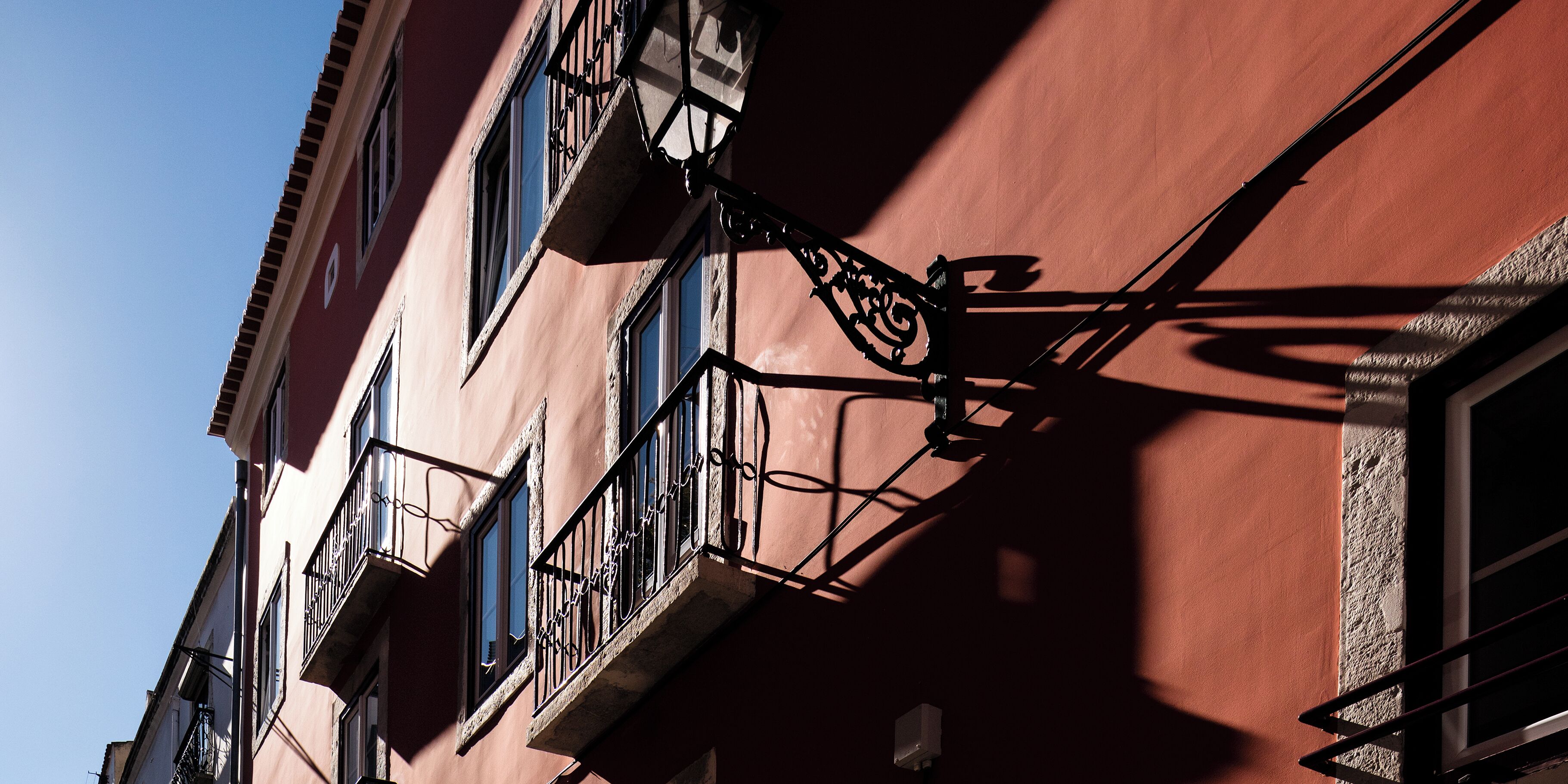 A building with multiple windows and balconies, featuring wrought iron railings and a clear sky in the background.