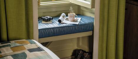 A bunk bed with a window, a book, a mug, and a pair of boots.