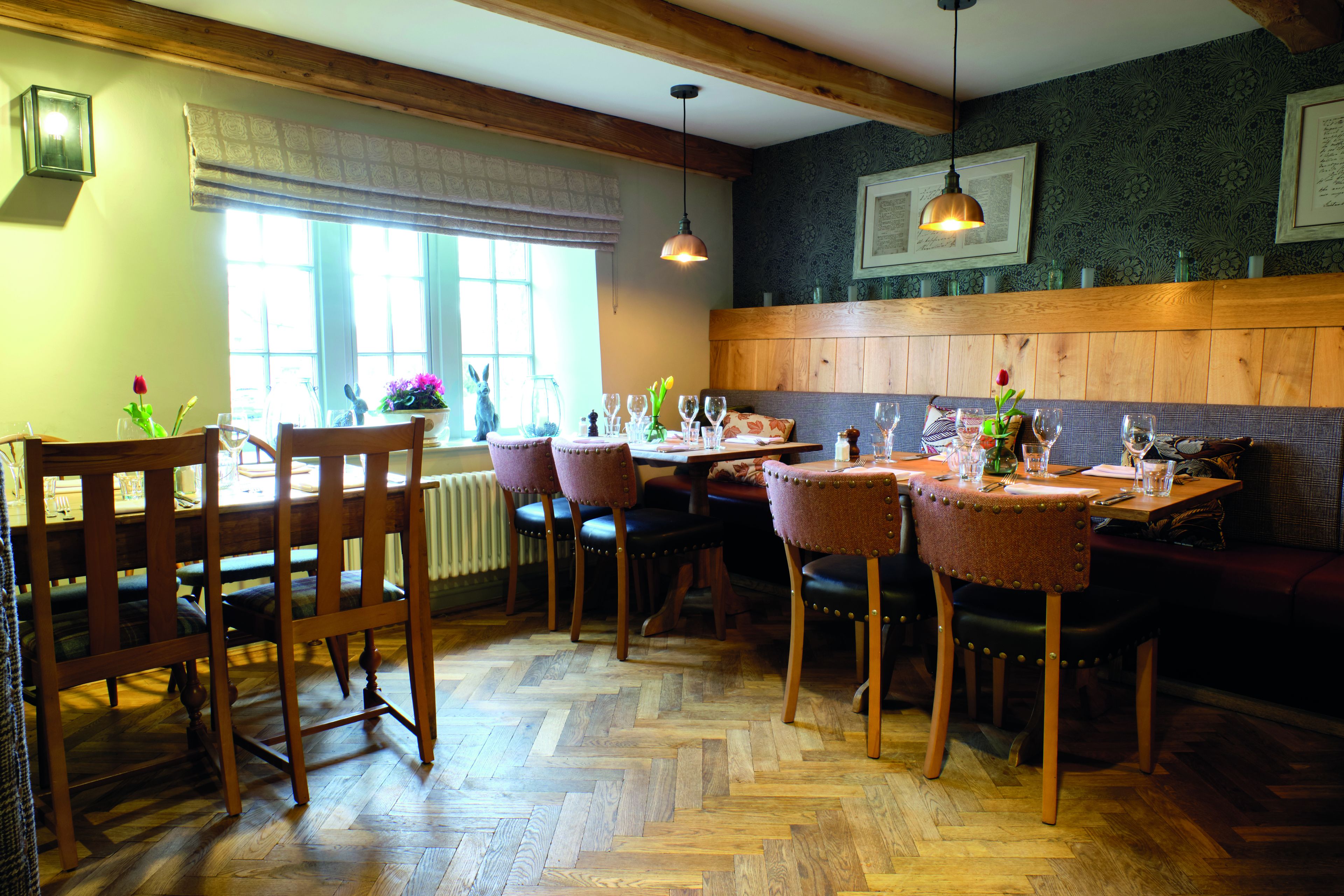 A dining area with wooden furniture, a herringbone floor, and a window with a view.