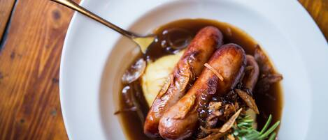 A white plate with two sausages, a spoon, and a garnish of herbs.