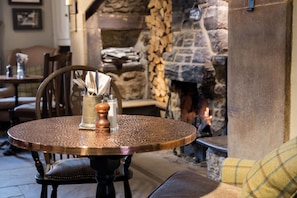 A round table with a copper finish, a glass vase with utensils, and a candle holder.