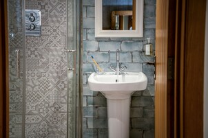 Un baño con un lavamanos blanco, un espejo encima y baldosas estampadas en las paredes.