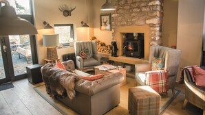A cozy living room with a stone wall, fireplace, and comfortable seating. - Lister Arms (Skipton)