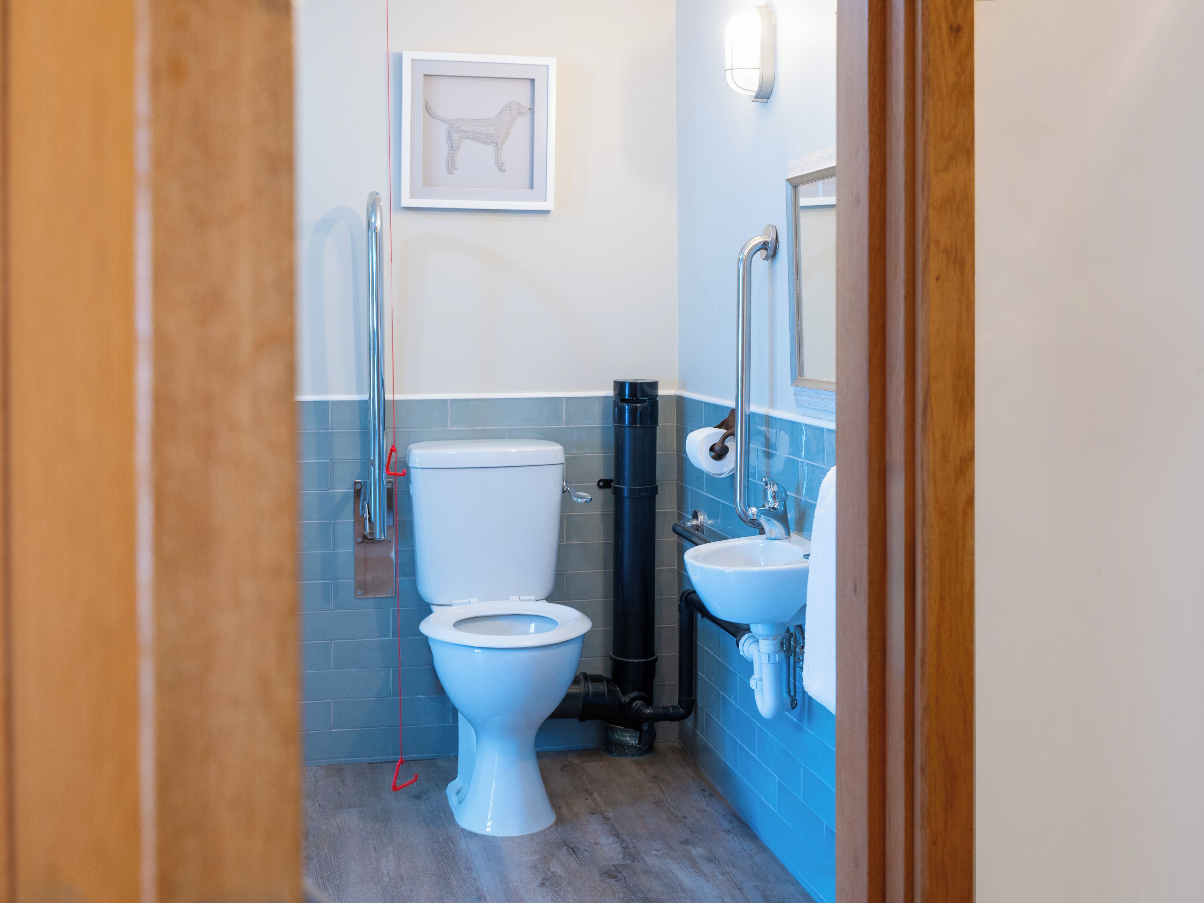 Un baño pequeño con inodoro, lavamanos y un cuadro en la pared.