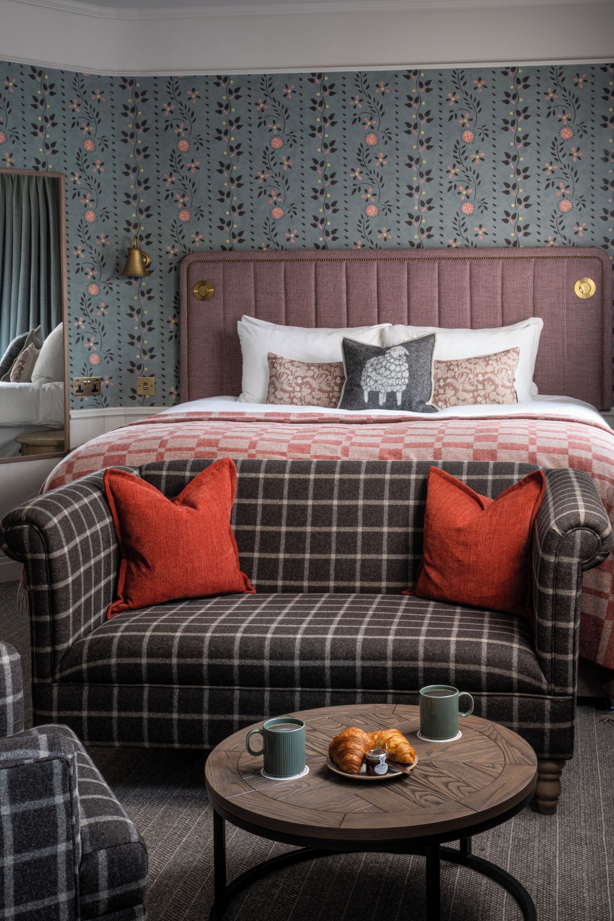 A bedroom with a bed, a sofa, and a coffee table with pastries and cups.