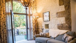 A cozy room with a stone wall, a grey sofa with patterned cushions, a lamp, and a framed picture. - Lister Arms (Skipton)