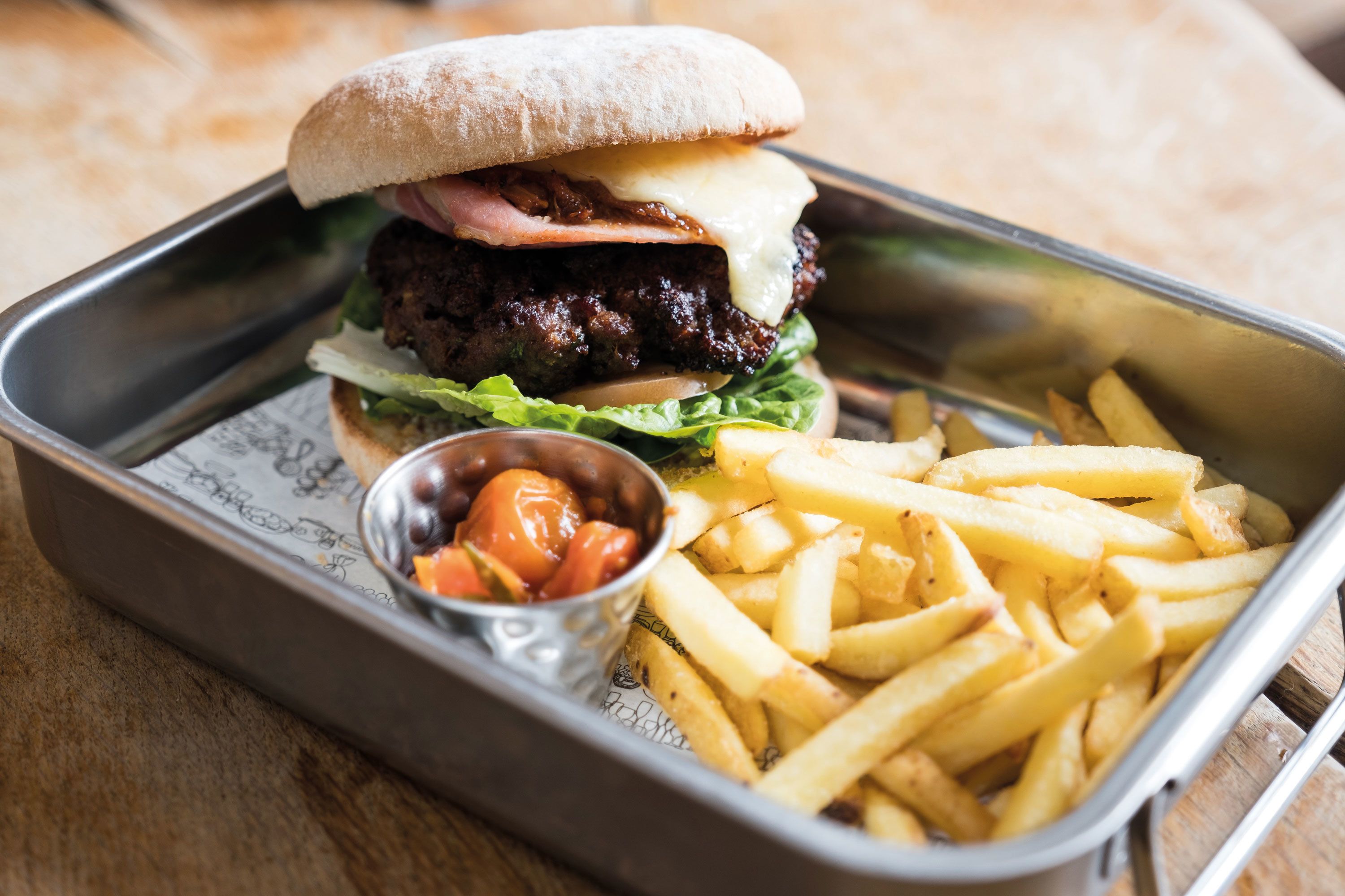 A meal consisting of a burger, fries, and ketchup in a metal tray.