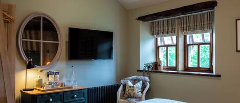 A bedroom with a bed, dresser, mirror, TV, and window with curtains.