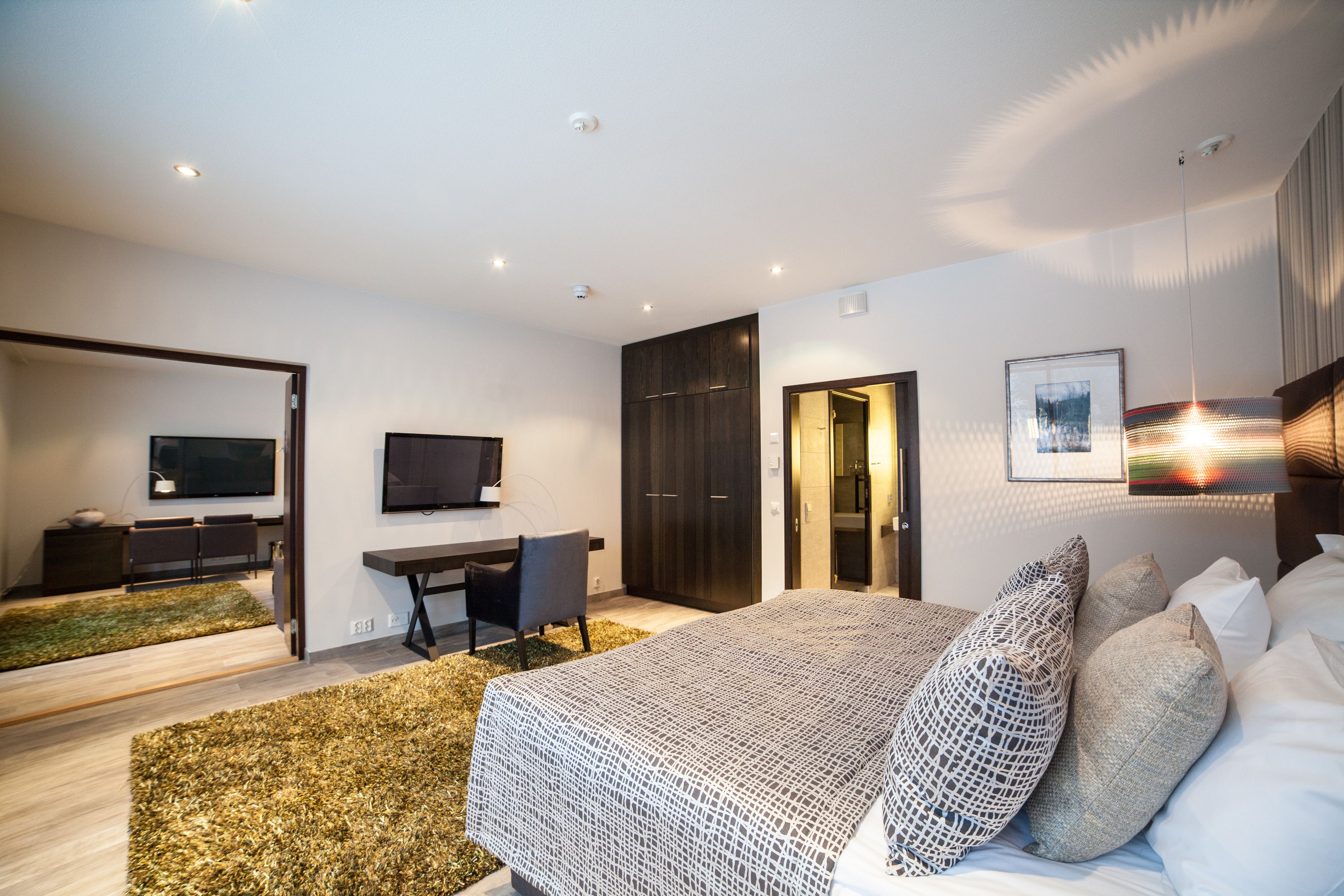 Un dormitorio moderno con cama, escritorio y televisión.