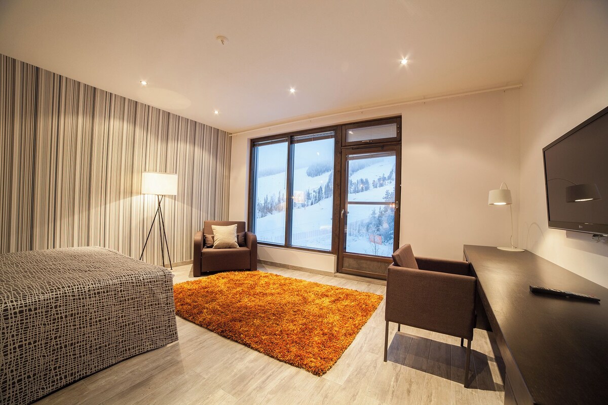 Un hotel moderno con una ventana grande, un sofá, un escritorio y un televisor.