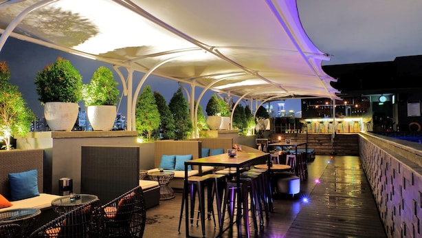 An outdoor seating area with tables and chairs, a bar, and potted plants. - Mercure Jakarta Cikini (Jakarta)