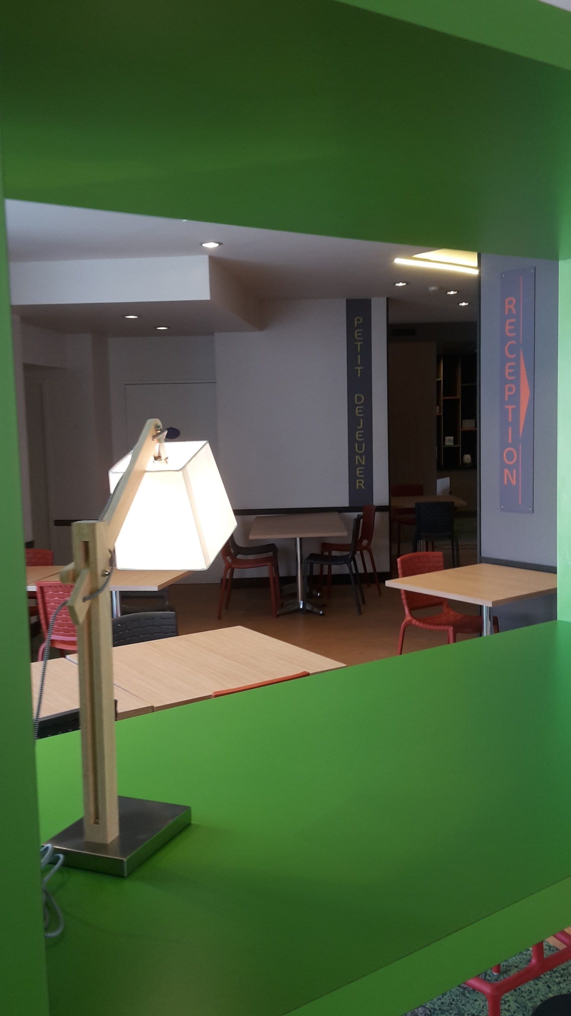Una habitación con escritorio, sillas, lámpara y cartel de recepción.
