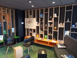 Una biblioteca con estanterías, un sofá, sillas y un mapa en la pared.