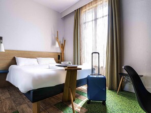 Ein Hotelzimmer mit Bett, Schreibtisch, Koffer und Stuhl.