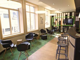 Un interior moderno con ventanas amplias, una zona de bar y diferentes disposiciones de asientos.