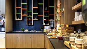 Een moderne keuken met houten kastjes, een aanrecht met diverse etenswaren en kleurrijke planken met keukengerei.