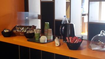 A bar area with stools, a coffee machine, and various food and drink containers.