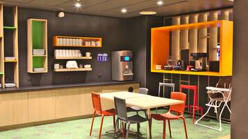 A modern cafe with a wooden counter, shelves with cups and a coffee machine, and a table with chairs.