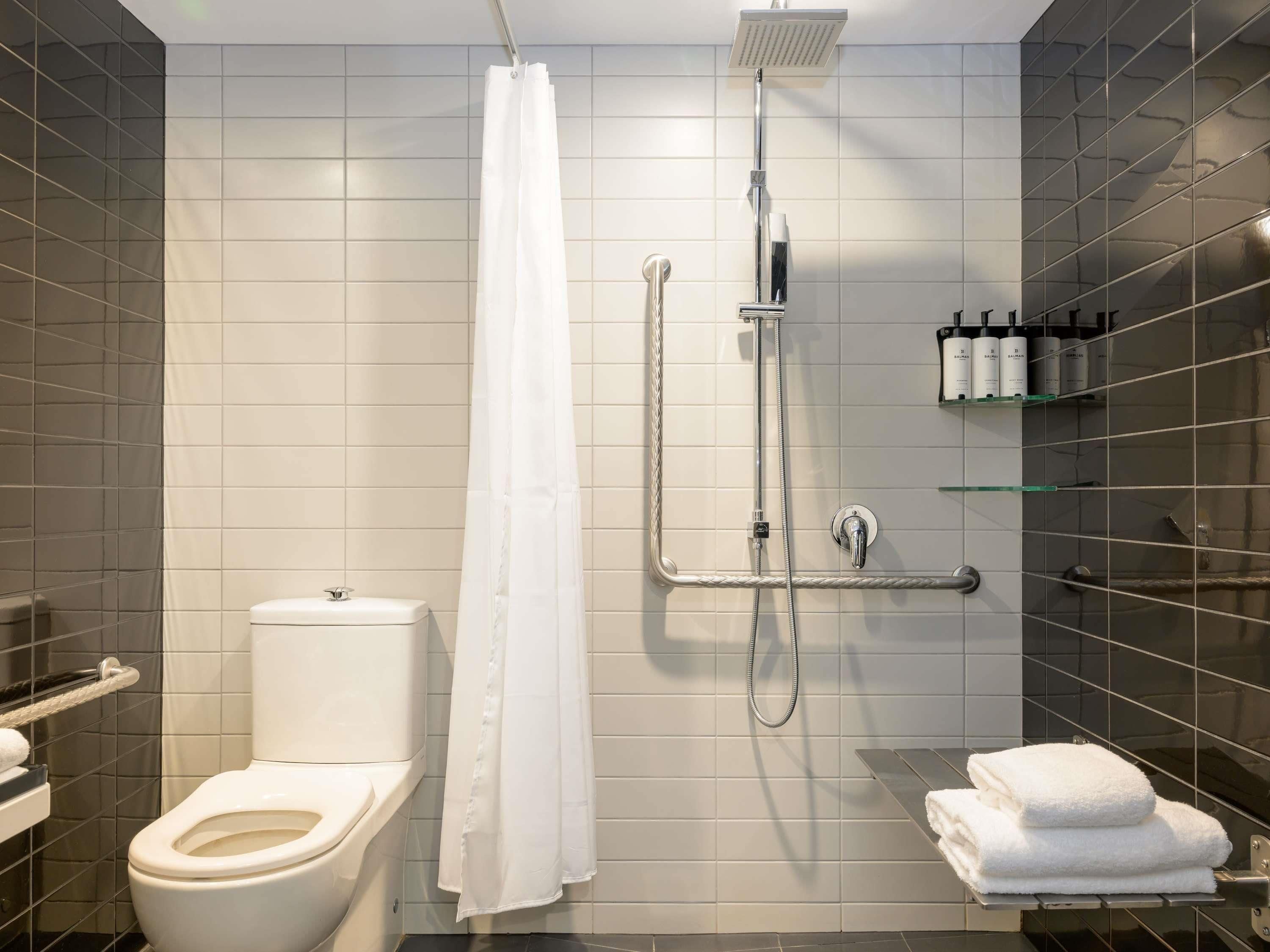 Un baño moderno con inodoro, ducha y perchero para toallas.
