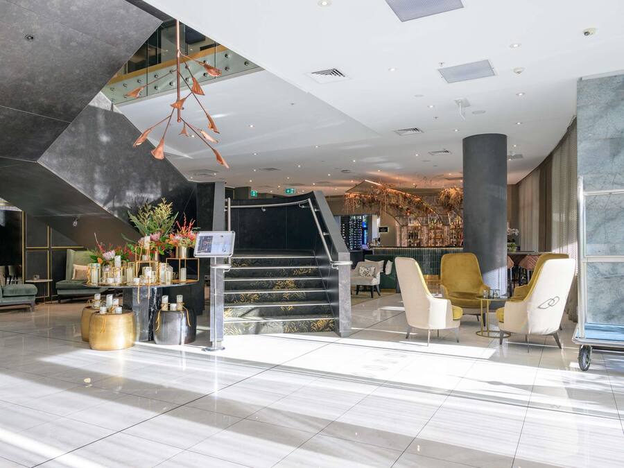 Een moderne lobby met een trap, zithoek en bar.