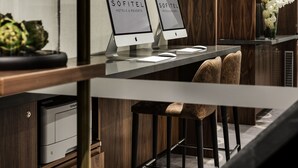 A reception desk with two monitors displaying "SOFITEL HOTELS & RESORTS" signage, a vase with white flowers, and a wooden panel backdrop. - Sofitel Wellington (Wellington)