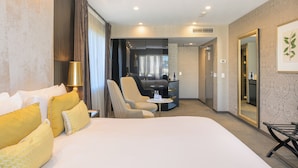 A hotel room with a large bed, two armchairs, a small table, and a mirror. - Sofitel Wellington (Wellington)