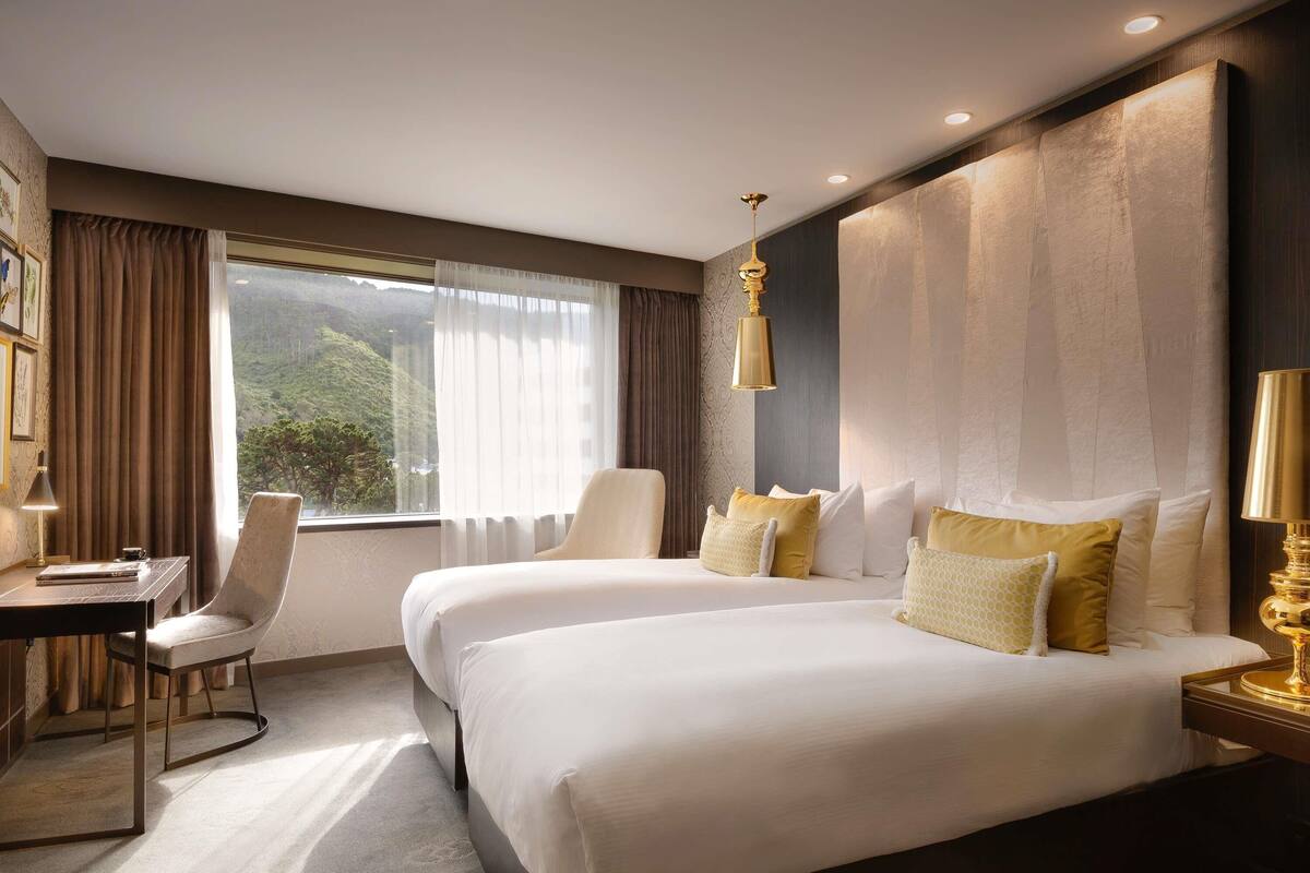 A hotel room with a large bed, a desk, and a chair.