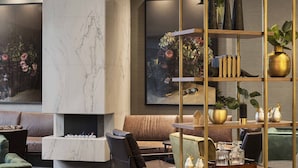 Una sala de estar moderna con chimenea de mármol, asientos cómodos y un estante decorativo con plantas y jarrones.