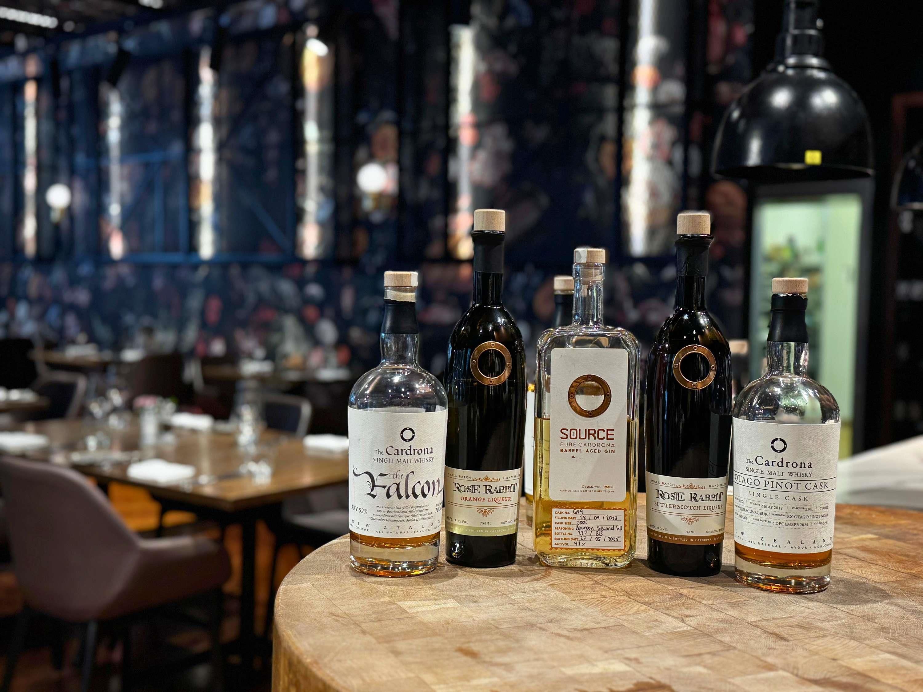 A selection of whisky bottles on a wooden table in a bar setting.