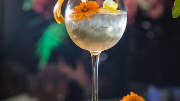 Un vaso de cóctel con hielo y una decoración floral sobre una superficie reflectante.