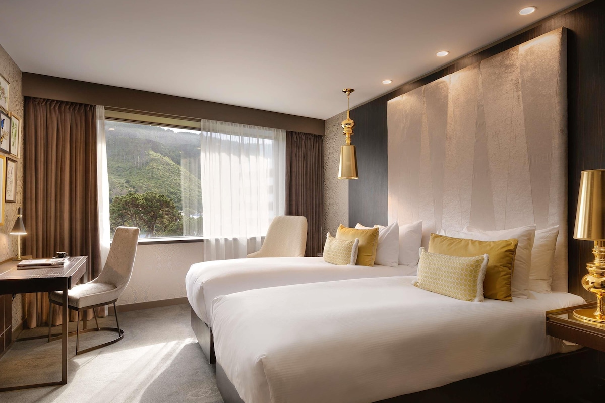 A hotel room with a large bed, a desk, and a chair.