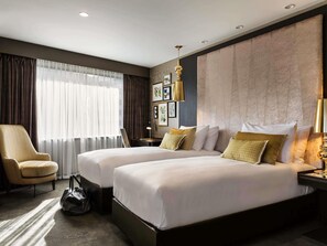 A hotel room with two beds, a chair, a desk, and a large window with curtains. - Sofitel Wellington (Wellington)