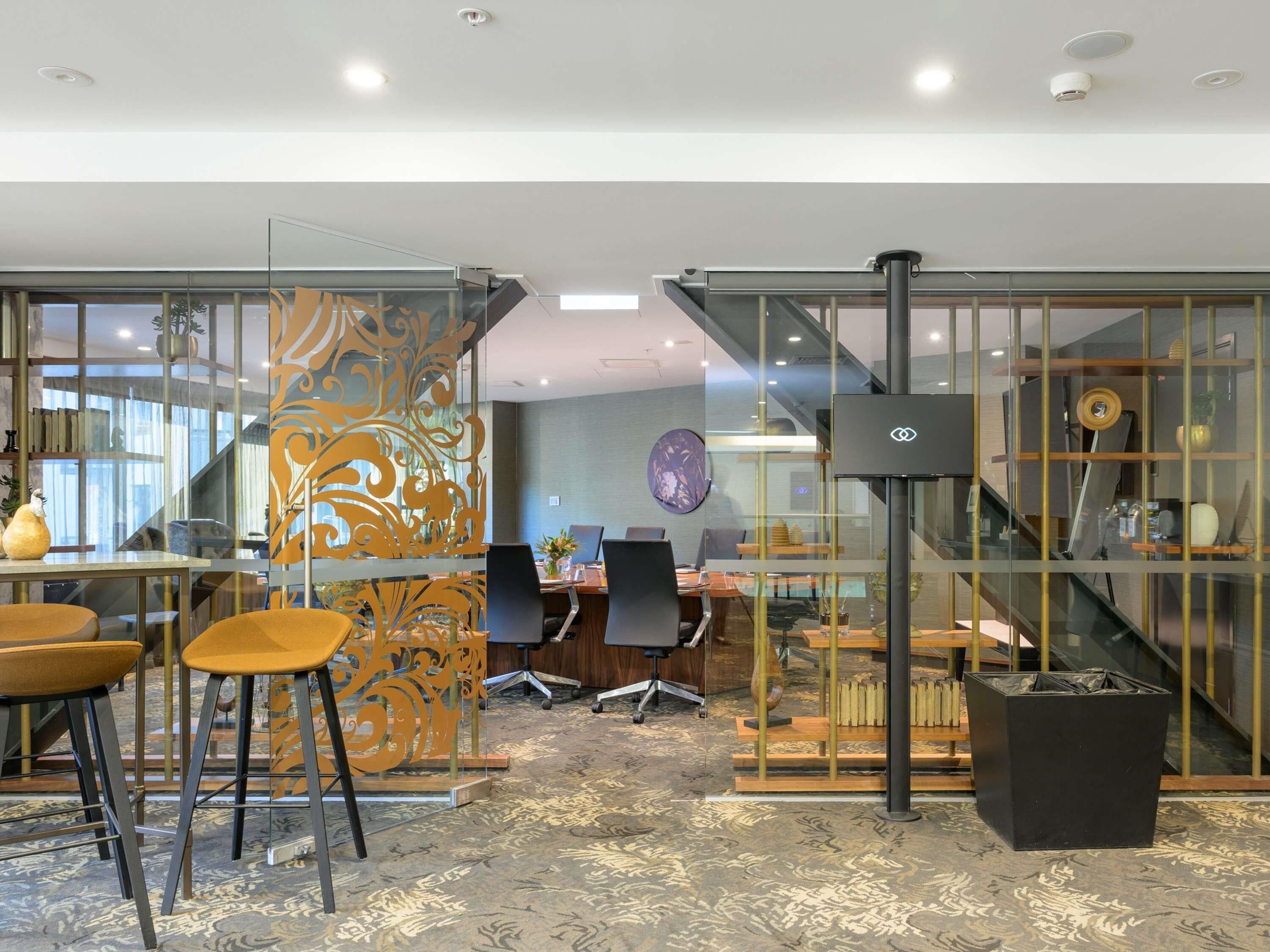 A modern office space with glass partitions, a staircase, and a conference table.