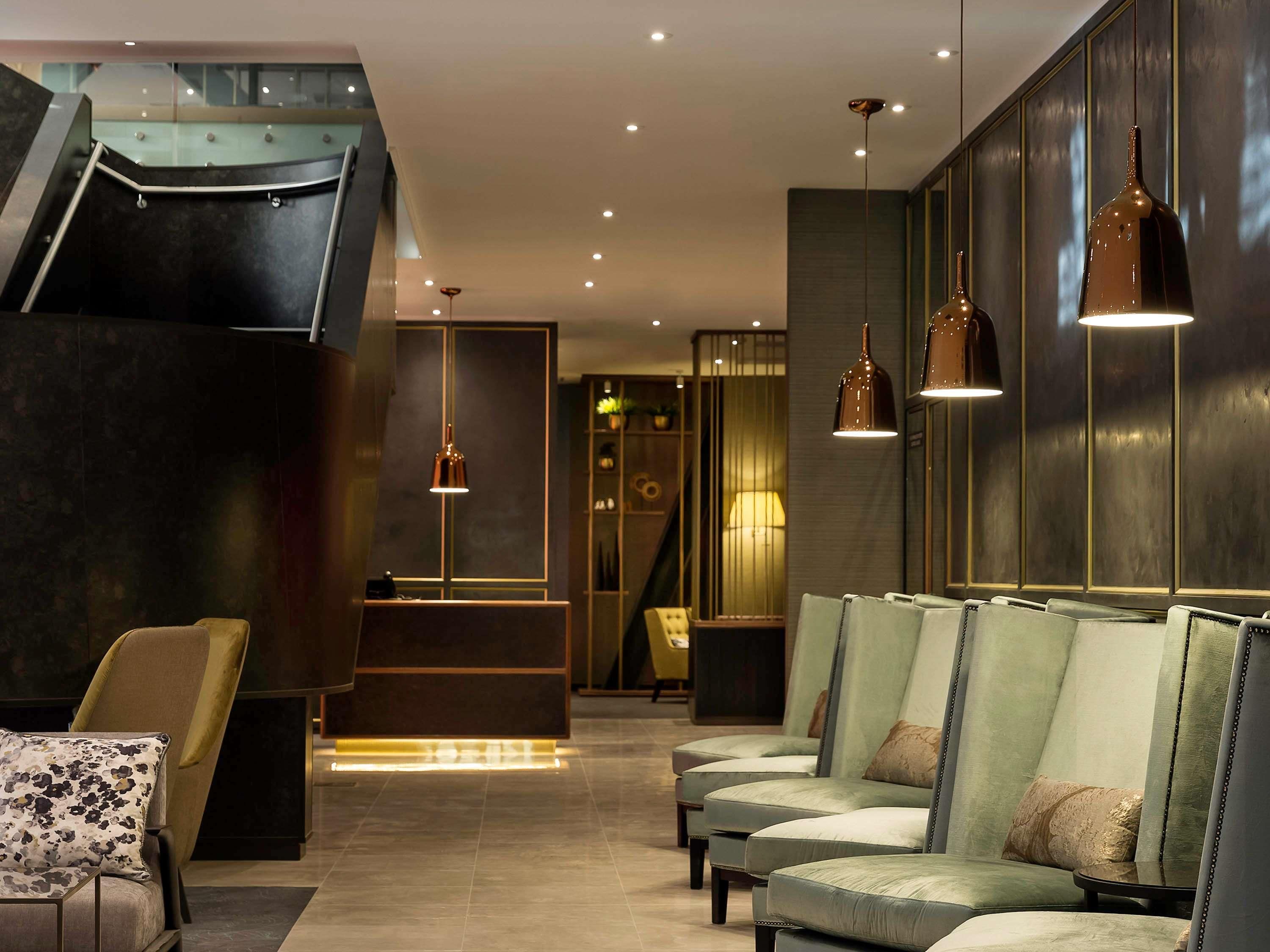 Eine moderne Lobby mit Empfangstresen, Sitzgelegenheiten und einer Treppe.