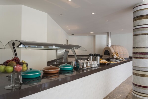 A modern kitchen with a built-in oven, a fruit bowl, and various kitchen appliances. - Sleep Inn Vitória Praia do Canto (Vitoria)