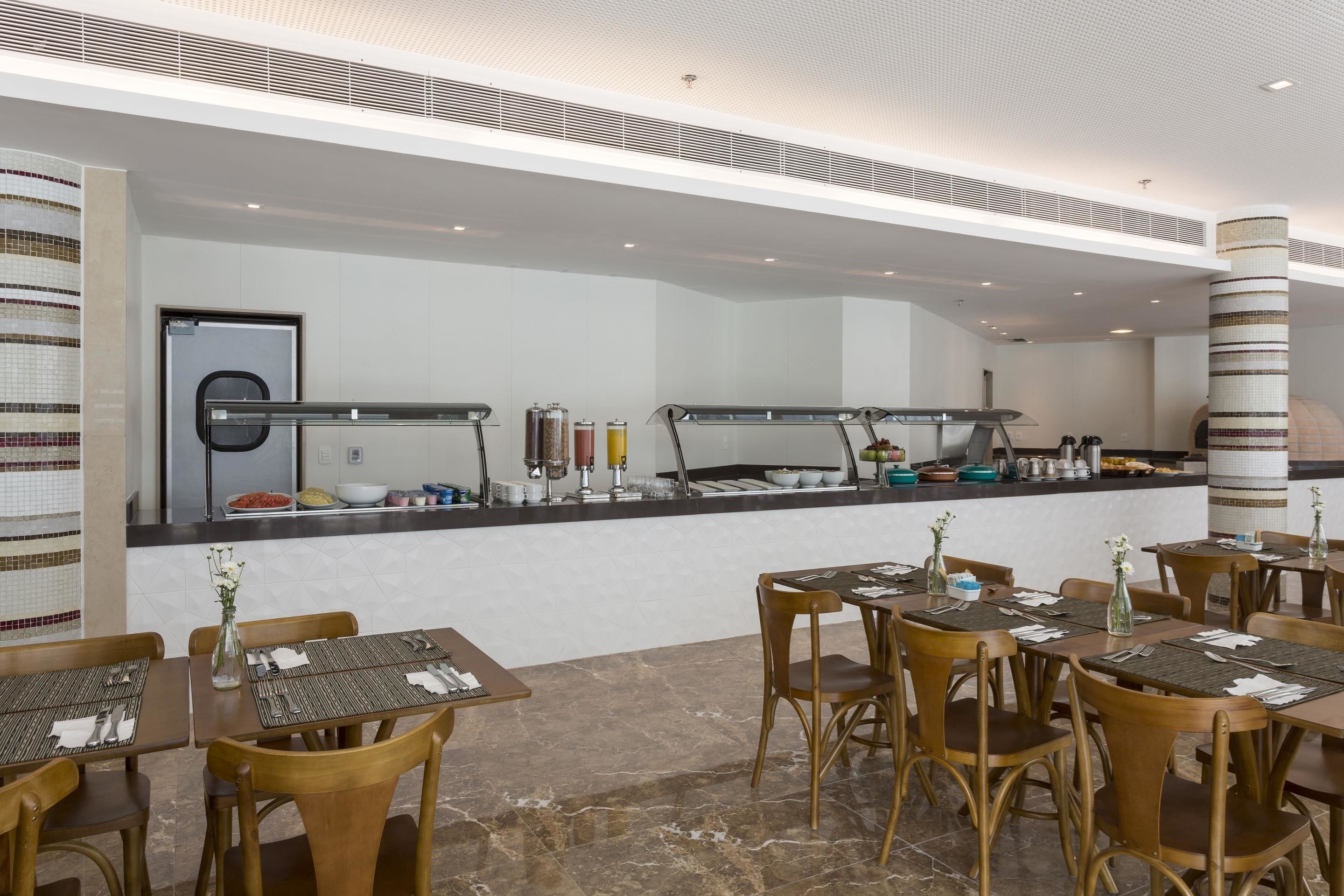 En moderne restaurant med en lang bardisk, flere siddeområder og en flisebeklædt væg.