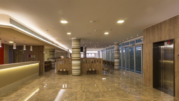 A spacious lobby with a polished marble floor, a central column, and a reception area with a counter and seating. - Sleep Inn Vitória Praia do Canto (Vitoria)