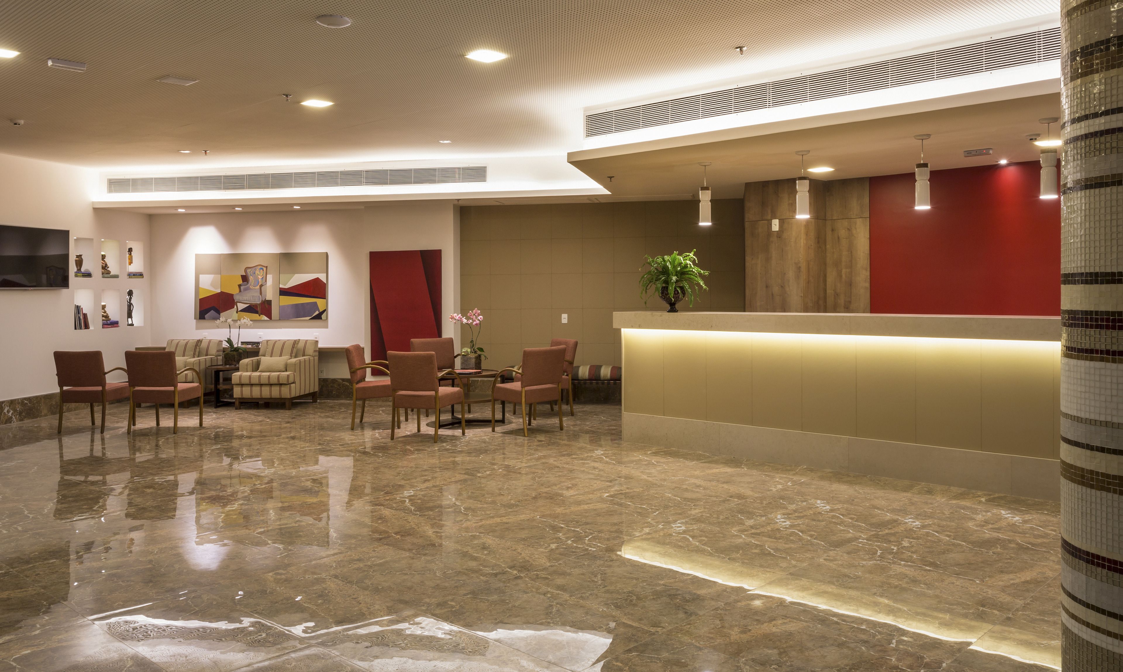 A lobby with a reception desk, seating area, and artwork on the walls.