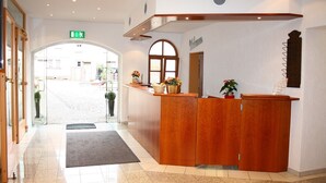 A reception area with a wooden reception desk, a welcome sign, and a potted plant.