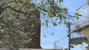 A courtyard with a pergola, outdoor seating, a staircase, and a brick wall.