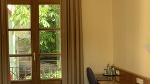 A hotel room with a bed, a desk, a chair, and a window with curtains.