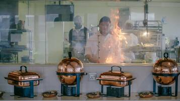 Una cocina con utensilios de cobre y un chef trabajando detrás de un separador de vidrio.