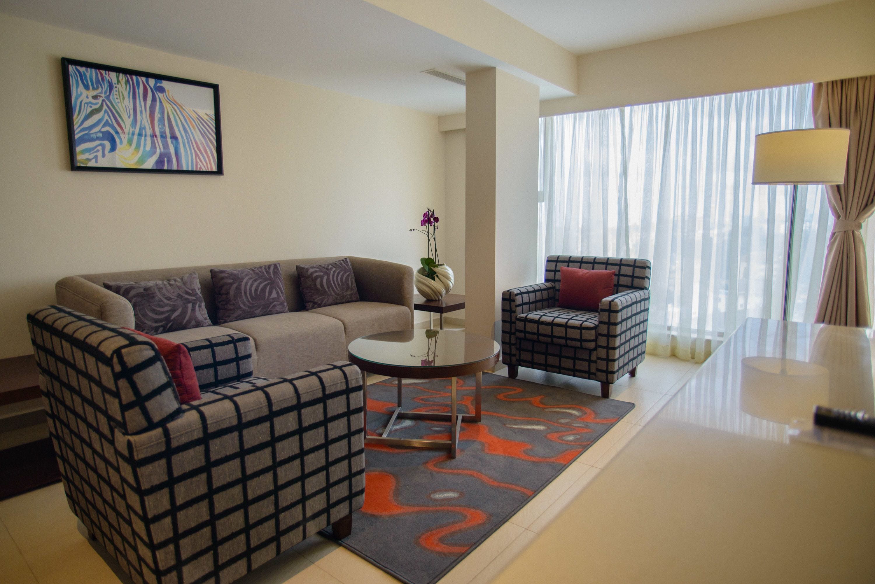 A modern living room with a sofa, armchair, and a small table with a vase.