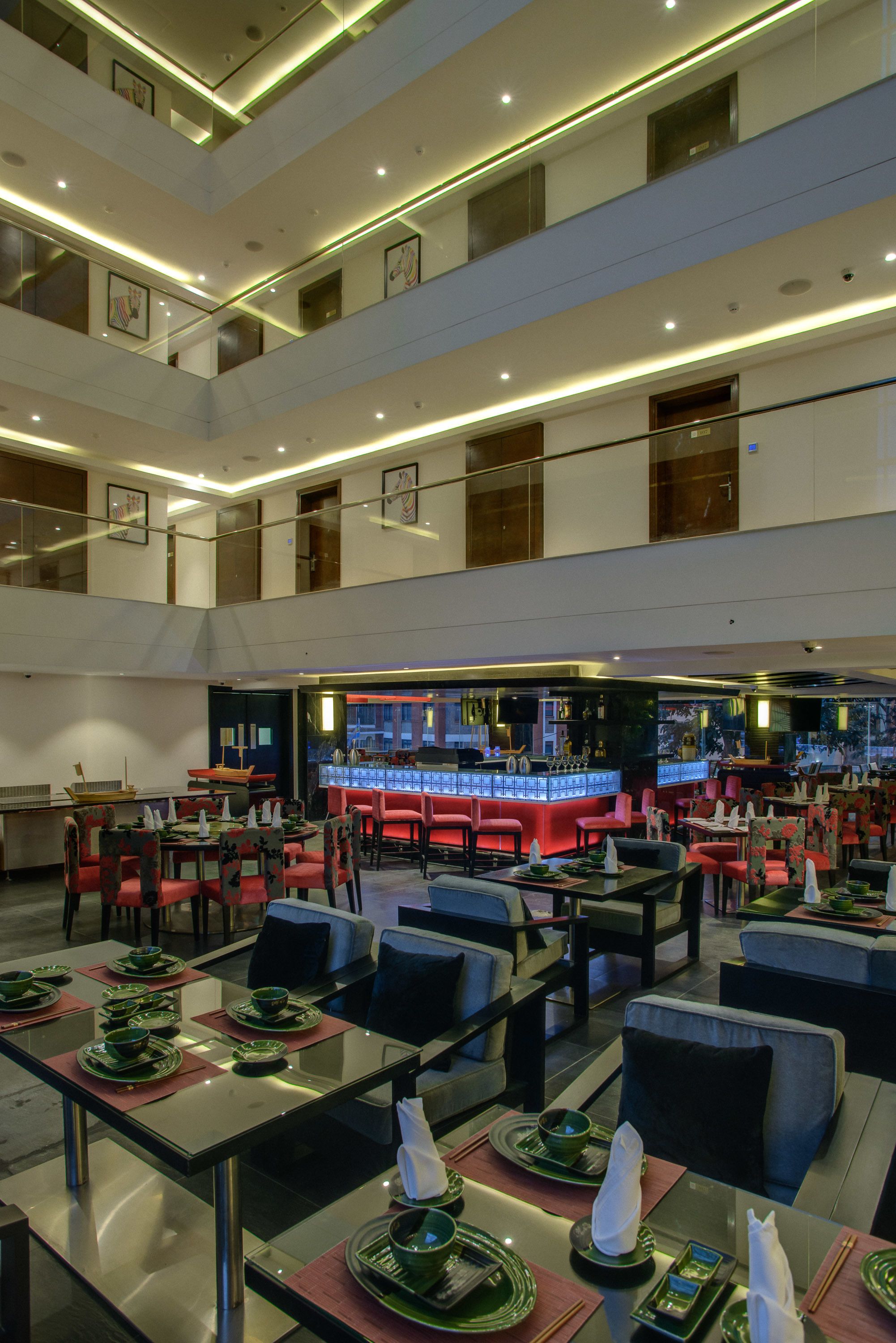 A multi-level restaurant with tables and chairs, a bar area, and a view of the cityscape.