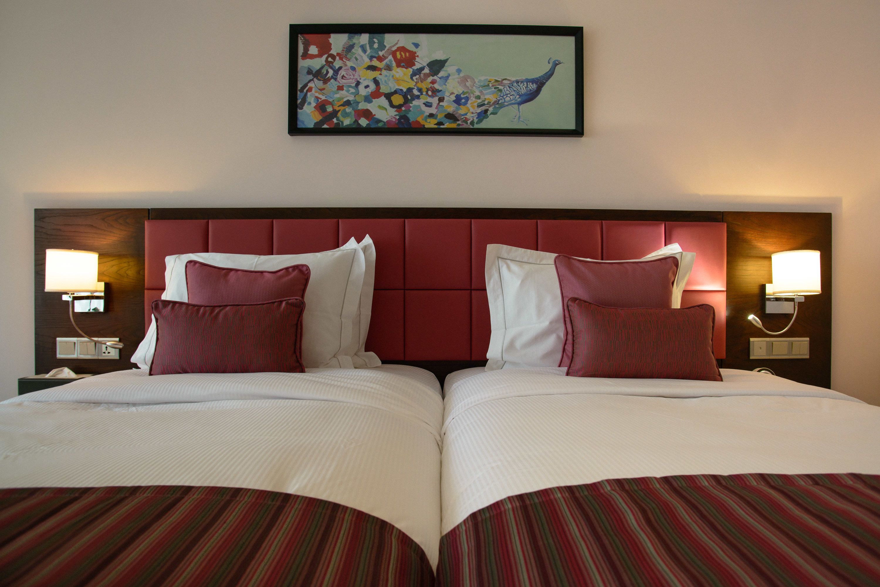 Una cama doble con cabecera roja, dos almohadas y una colcha a rayas.
