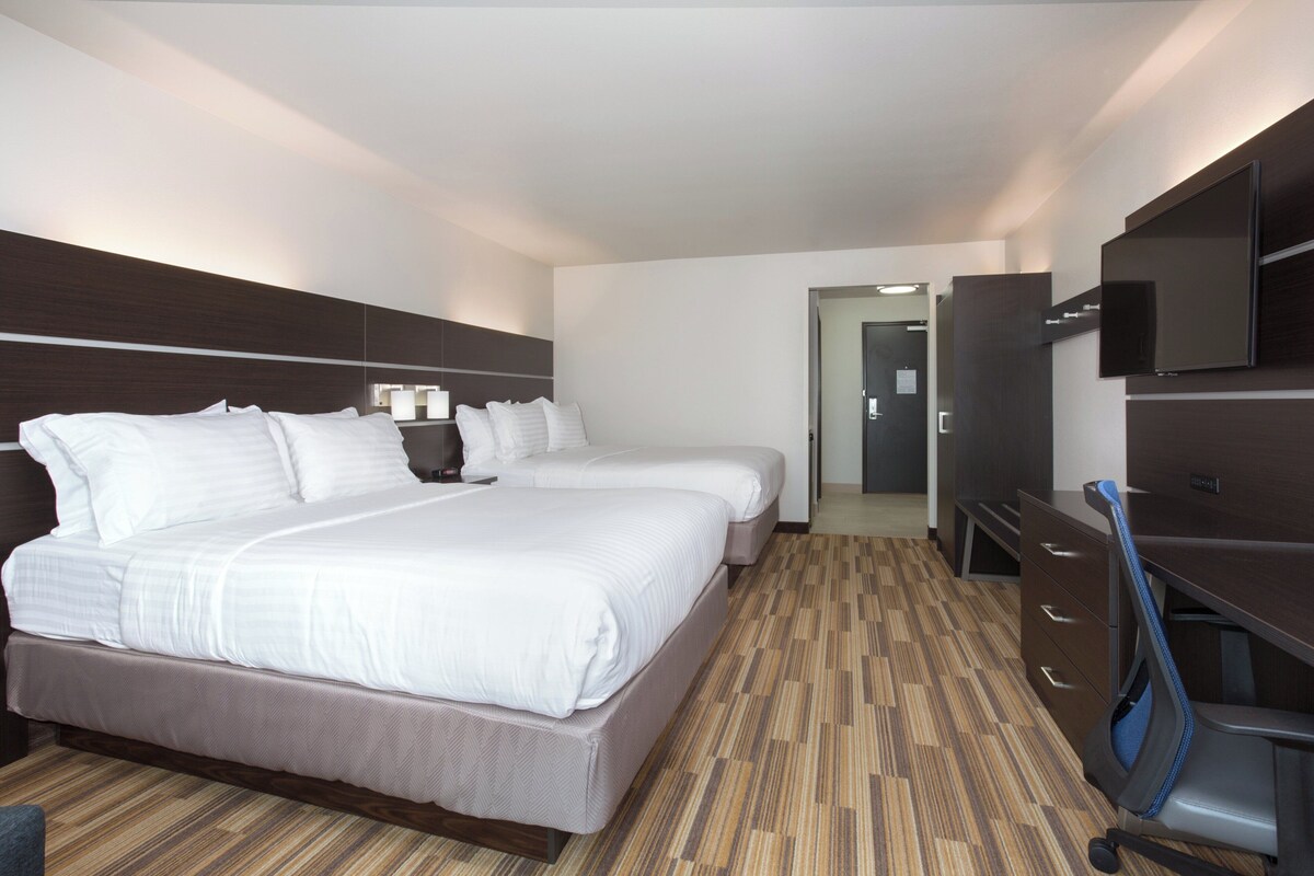 A hotel room with two beds, a desk, a TV, and a wardrobe.