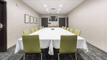 Una sala de conferencias con una mesa larga, sillas y una pantalla de televisión en la pared.