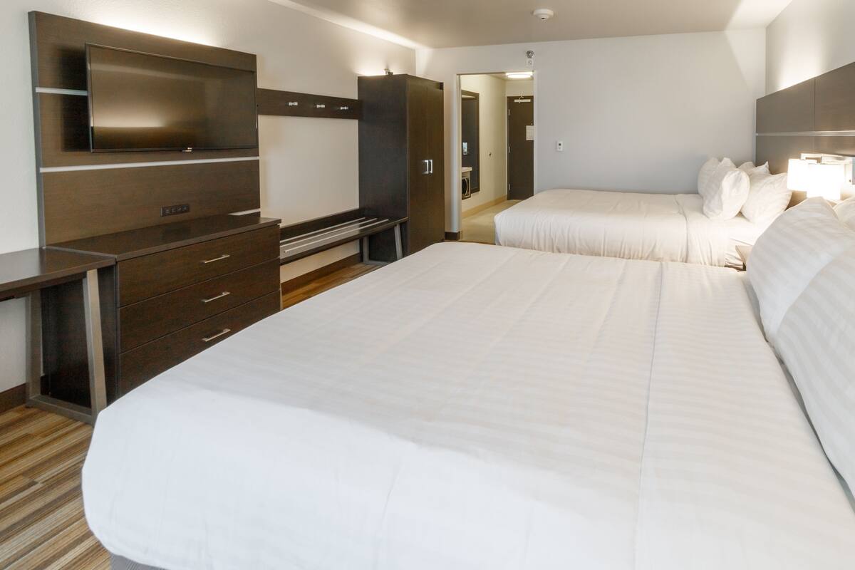 A hotel room with a large bed, a TV mounted on the wall, a desk, and a wardrobe.