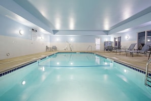 A swimming pool with a tiled edge, a changing room with a door, and a bench area with chairs. - Holiday Inn Express and Suites Lincoln I - 80 by IHG (Lincoln)