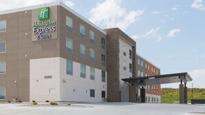 A Holiday Inn Express & Suites building with a modern design, featuring a flat roof, large windows, and a stone accent wall. - Holiday Inn Express and Suites Lincoln I - 80 by IHG (Lincoln)